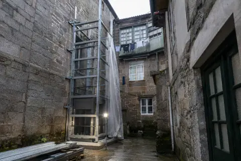 Estructura metálica de un ascensor exterior montándose en el patio interior de un edificio de piedra