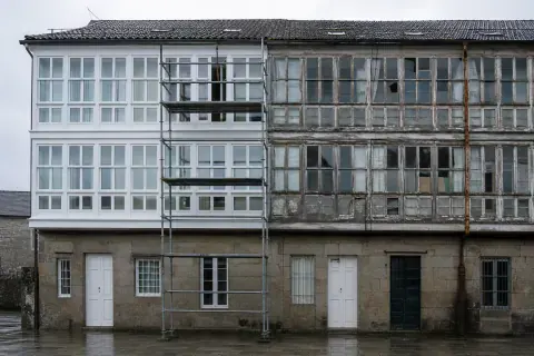 Edificio de viviendas con parte de la carpintería de madera ya sustituida y parte todavía vieja
