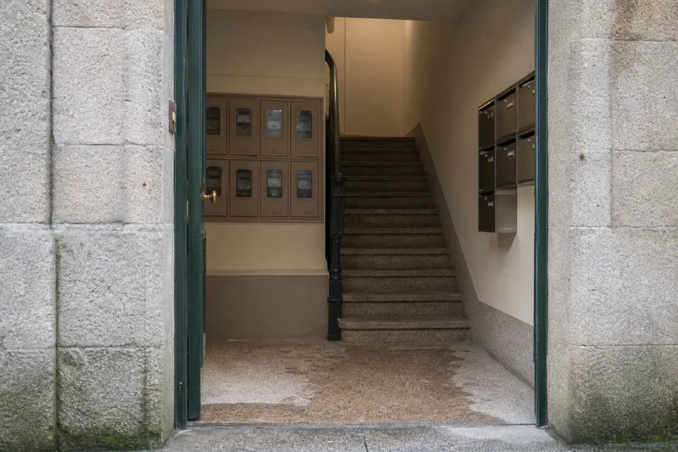 Normativa de ascensores en Vigo, portal con contadores y escalera de granito
