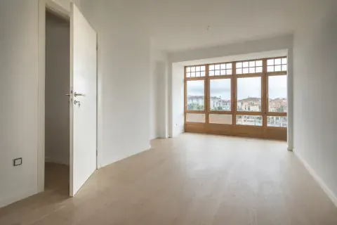 Vivienda terminada y vacía con suelo de madera nuevo y la luz gris entrando por la galería